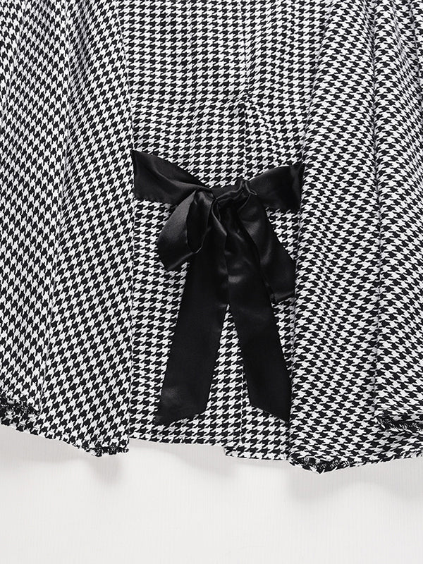Black and white houndstooth cape coat with a stand collar and tie belt