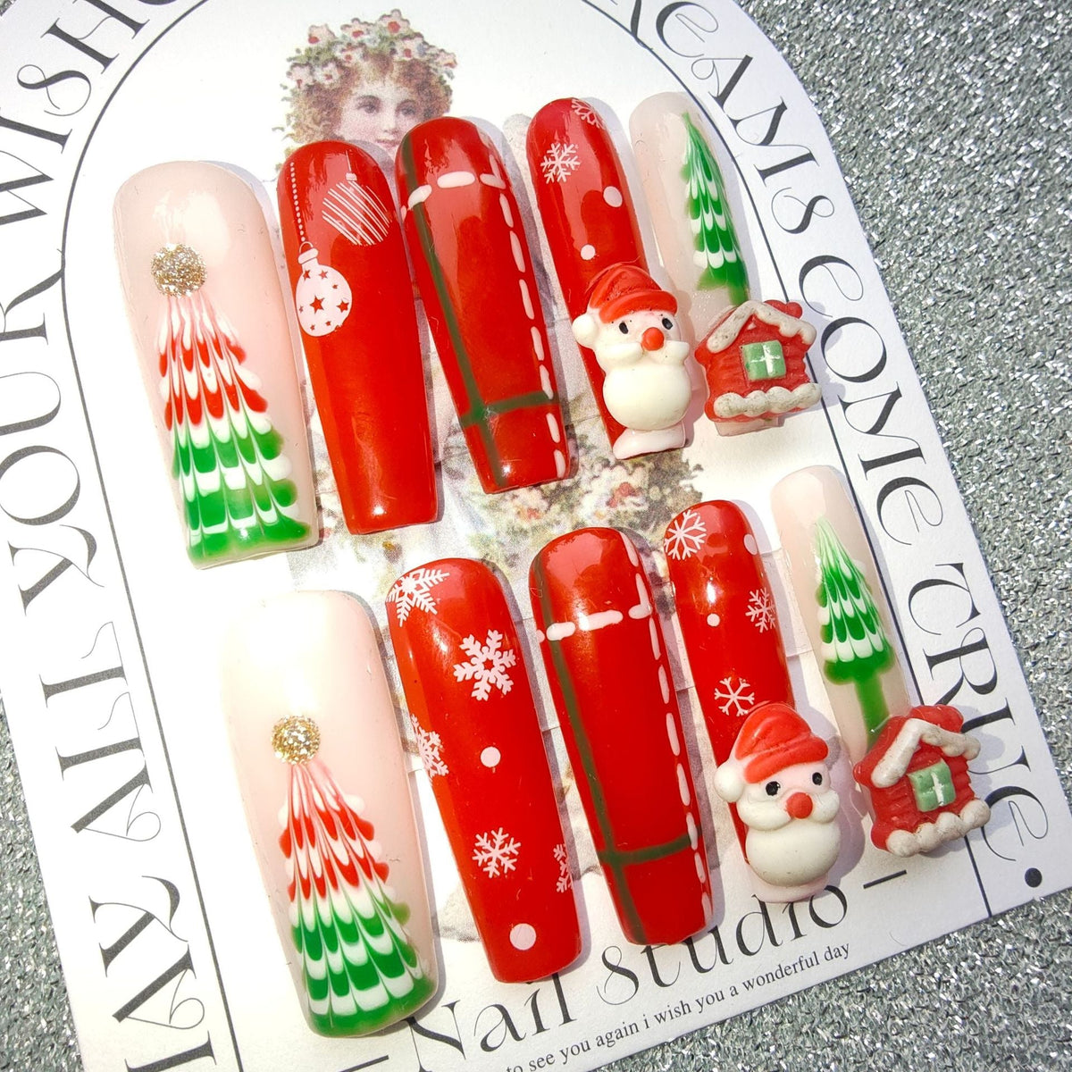 3D Christmas press-on nails with festive figures and bows on a display card - tree, father christmas and cottage