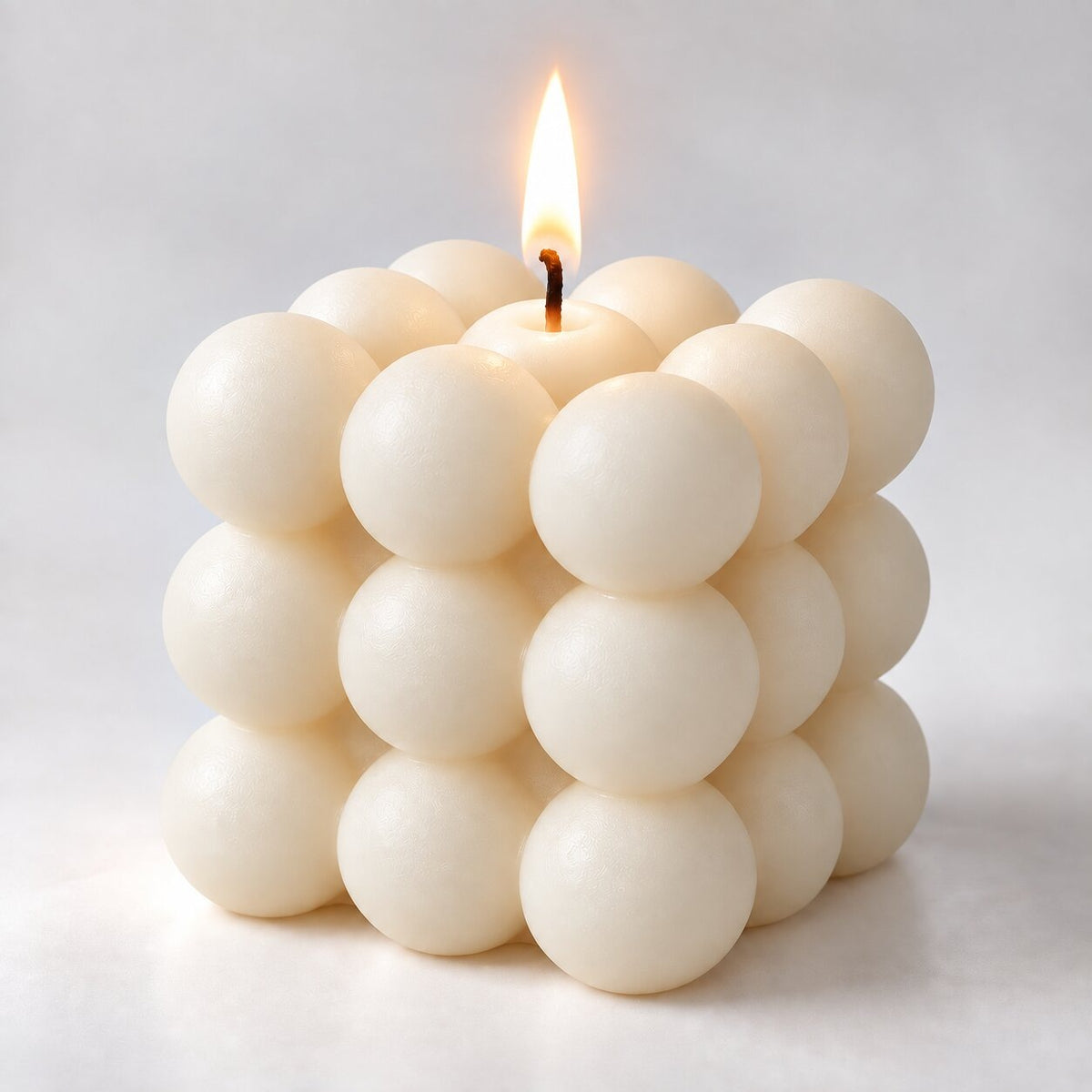 Bubble cube candle with a lit wick - white