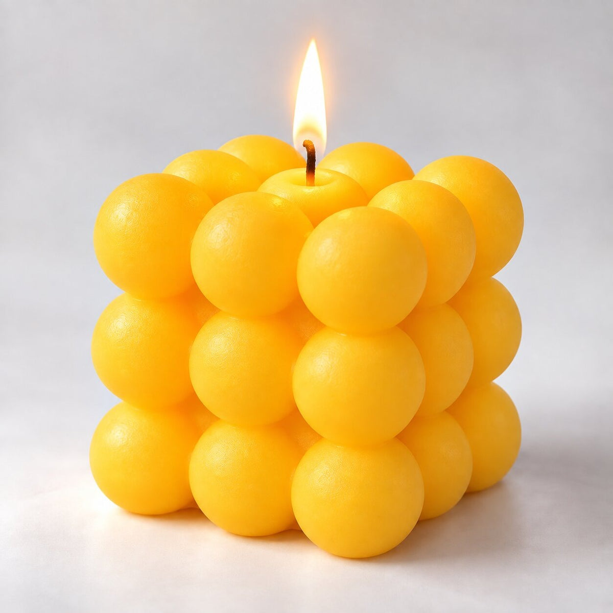 Bubble cube candle with a lit wick - yellow