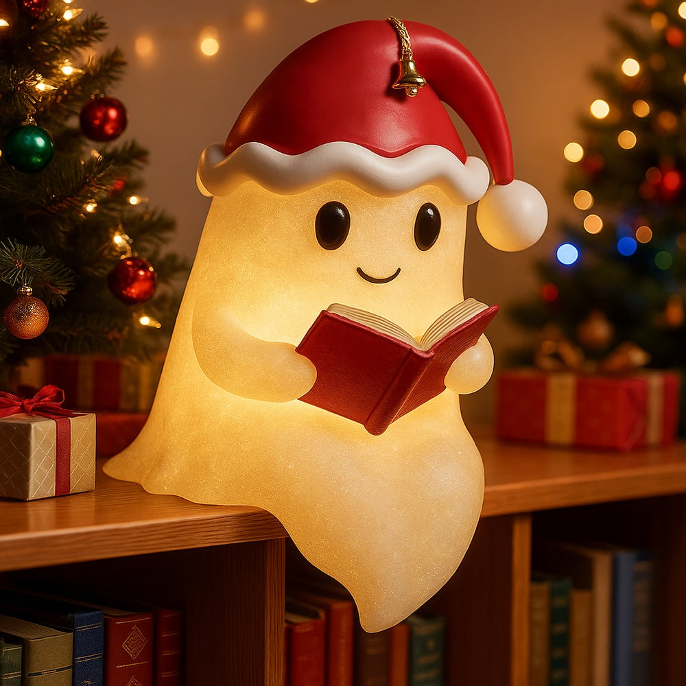White ghost lamp in a red Santa hat with a bell, holding a red book and glowing warm yellow