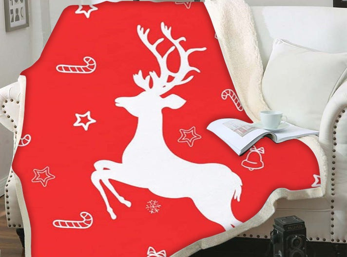 Christmas blanket with a teddy reverse and festive print, over an armchair - red leaping reindeer