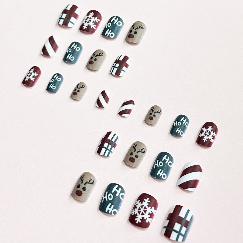 Christmas press-on nails with a festive print, applied on a hand