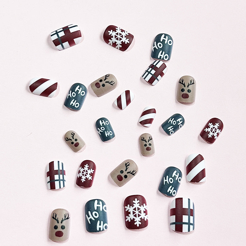 Christmas press-on nails with a festive print, applied on a hand