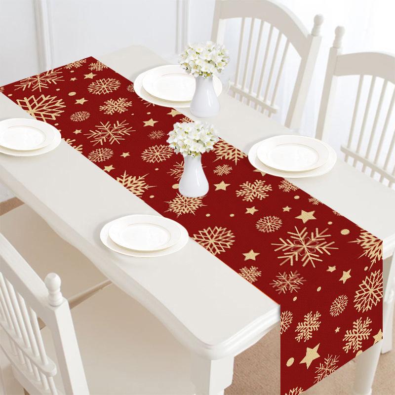 Christmas table runner, 30 x 180 cm, with a festive print on a laid table - dark red with gold snowflakes
