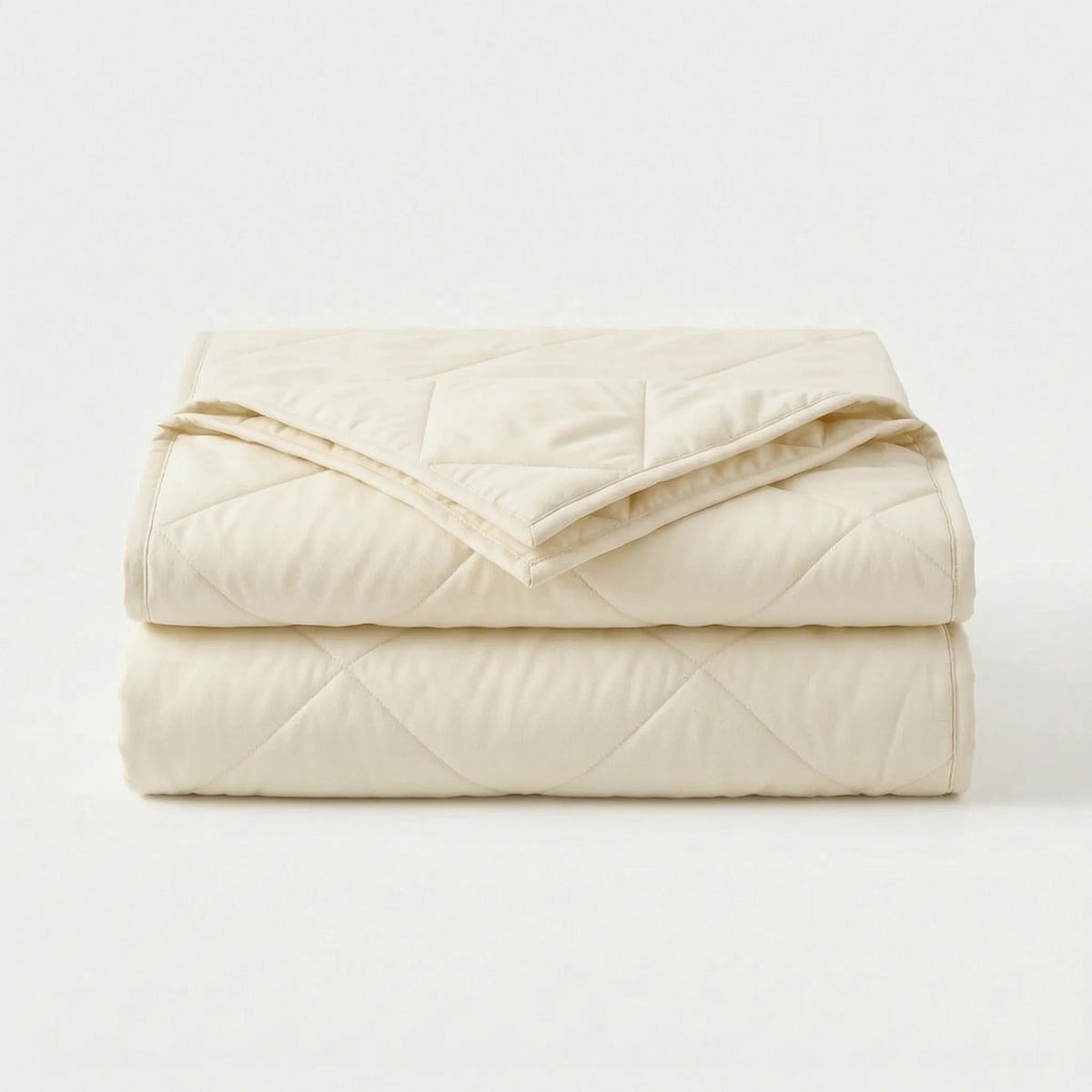 Light cooling blanket with diamond stitching over a made bed - off-white