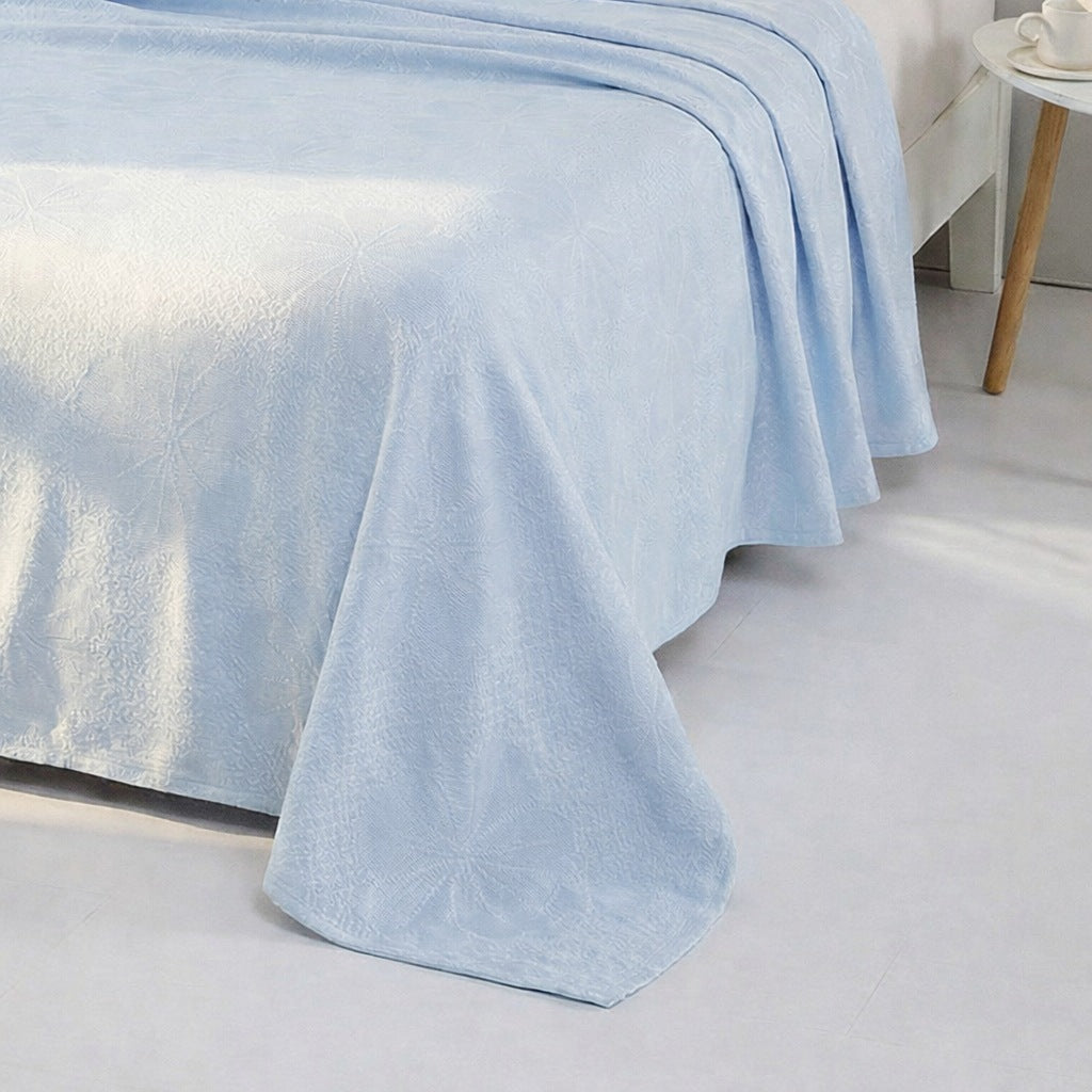 Cooling blanket with a woven floral pattern on a bed