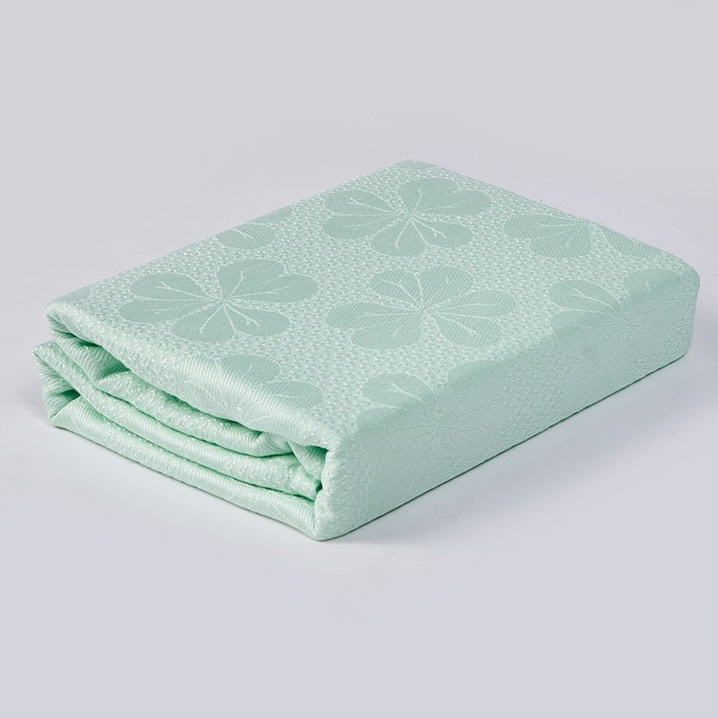Cooling blanket with a woven floral pattern on a bed - mint green