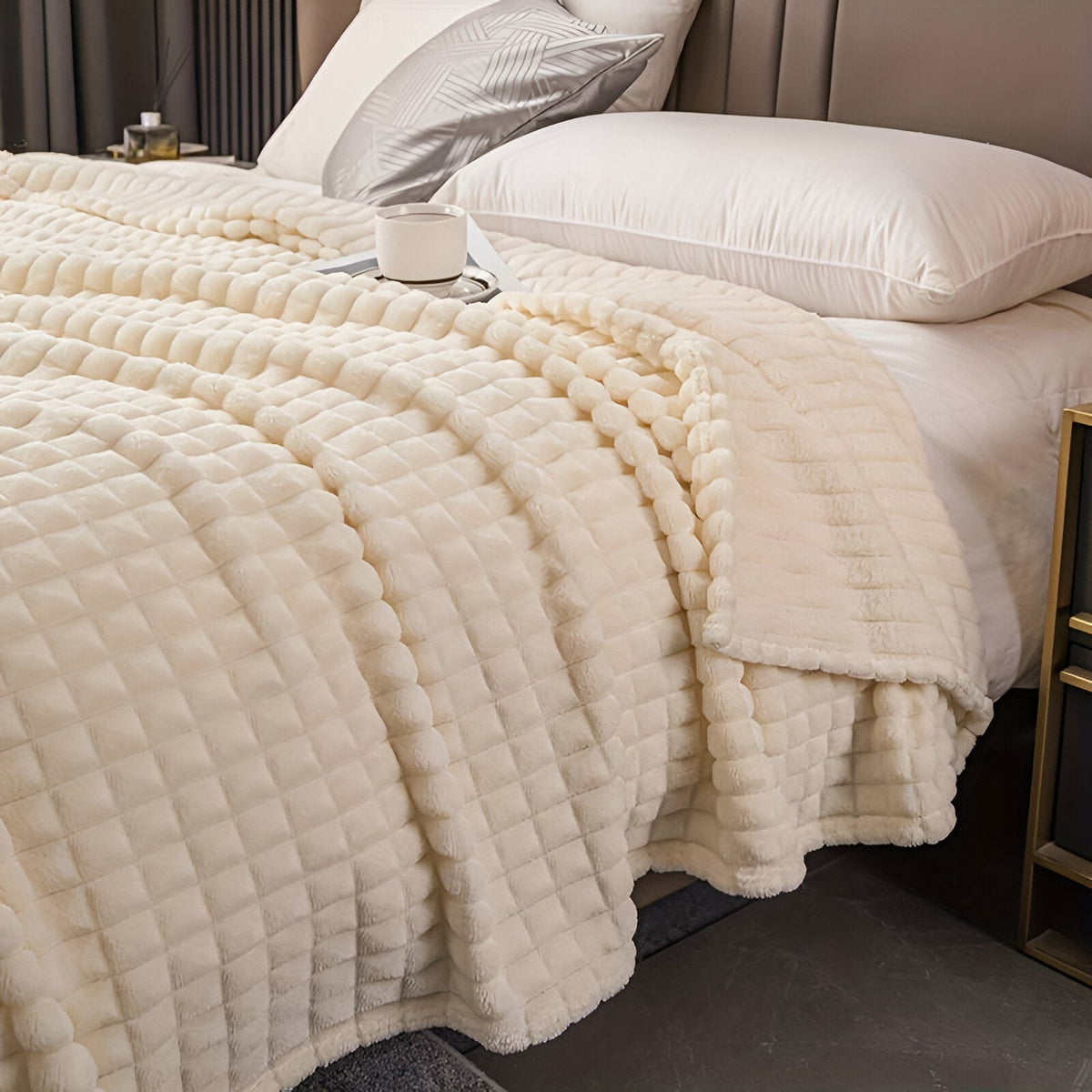 Coral fleece blanket with a square grid texture over a bed - cream