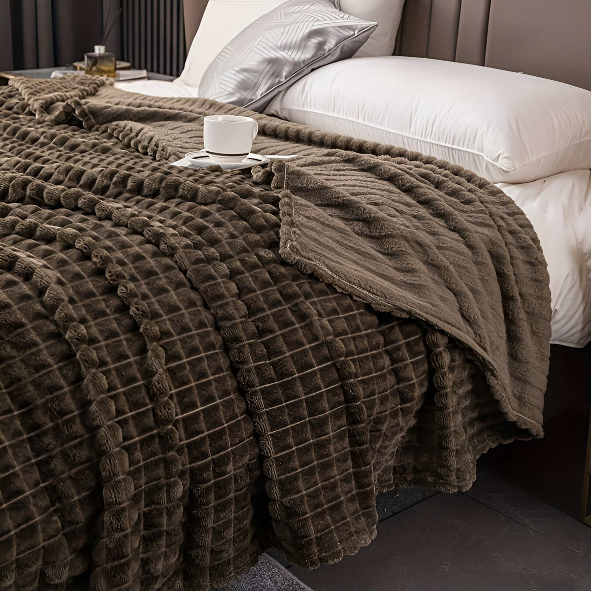 Coral fleece blanket with a square grid texture over a bed - taupe