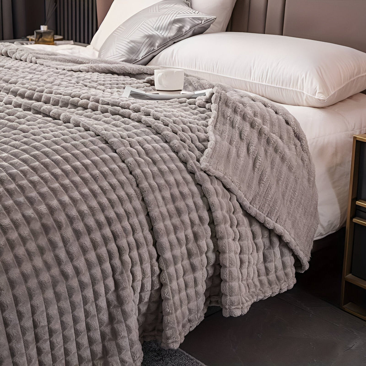 Coral fleece blanket with a square grid texture over a bed - light grey