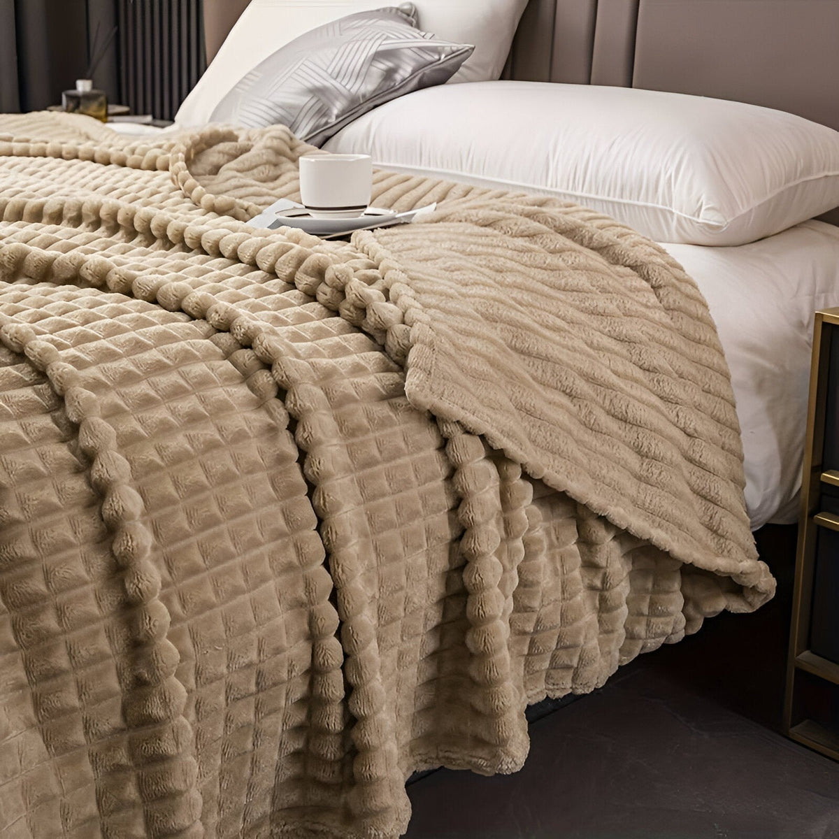 Coral fleece blanket with a square grid texture over a bed - camel
