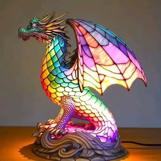 Dragon lamp in a stained glass look with rainbow scales and pink wings on a base with waves