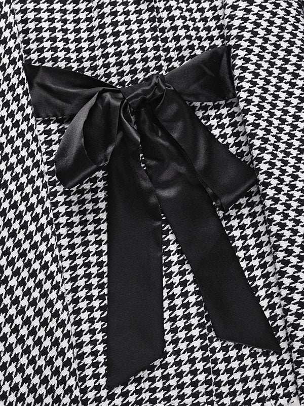 Black and white houndstooth cape coat with a stand collar and tie belt