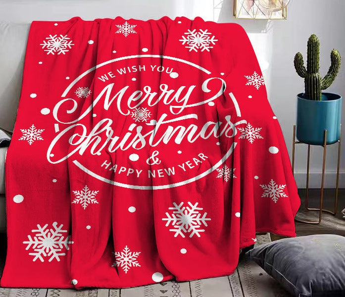 Soft fleece Christmas throw with a festive print, draped over a sofa - red merry christmas wreath