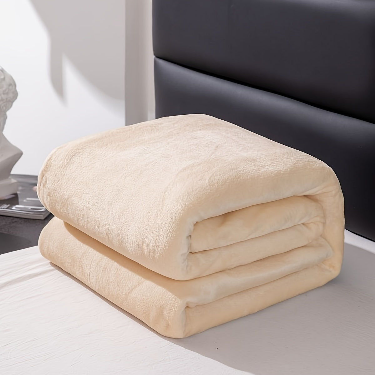 Plain flannel fleece blanket over a bed - cream
