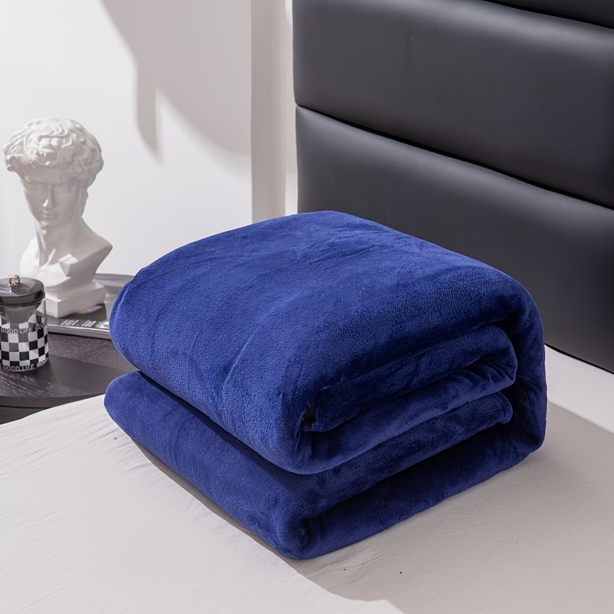 Plain flannel fleece blanket over a bed - royal blue
