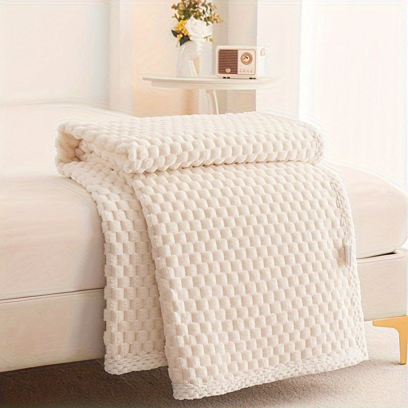 Fleece throw with a block texture and knitted trim draped over a bed - cream