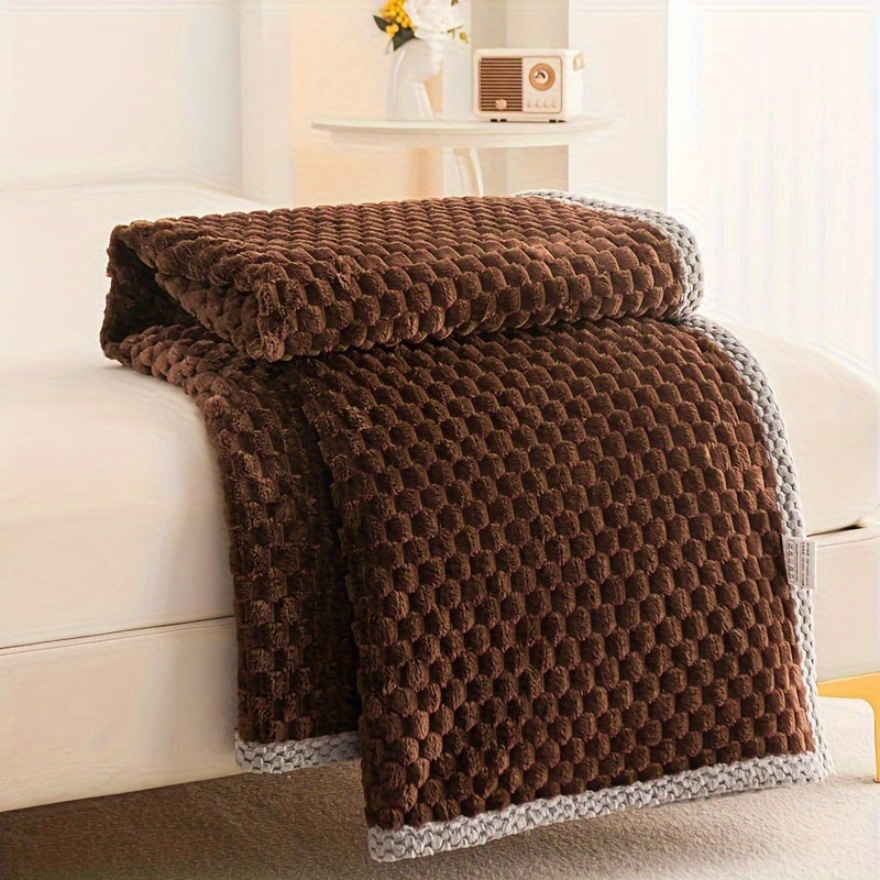 Fleece throw with a block texture and knitted trim draped over a bed - chocolate brown