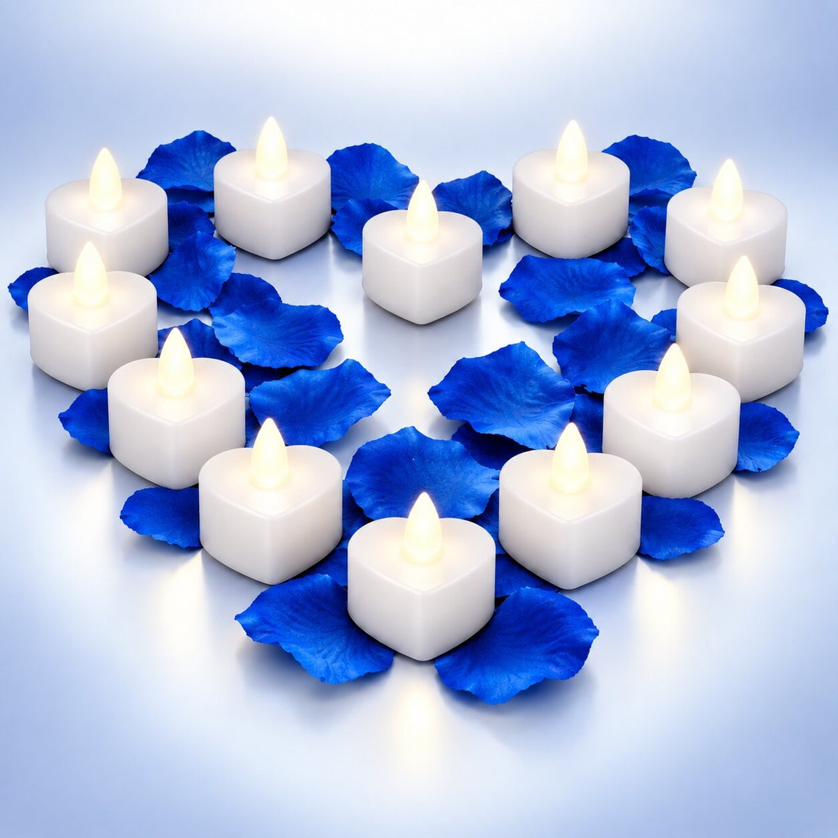 Heart-shaped LED tea lights with a flickering flame among rose petals - white