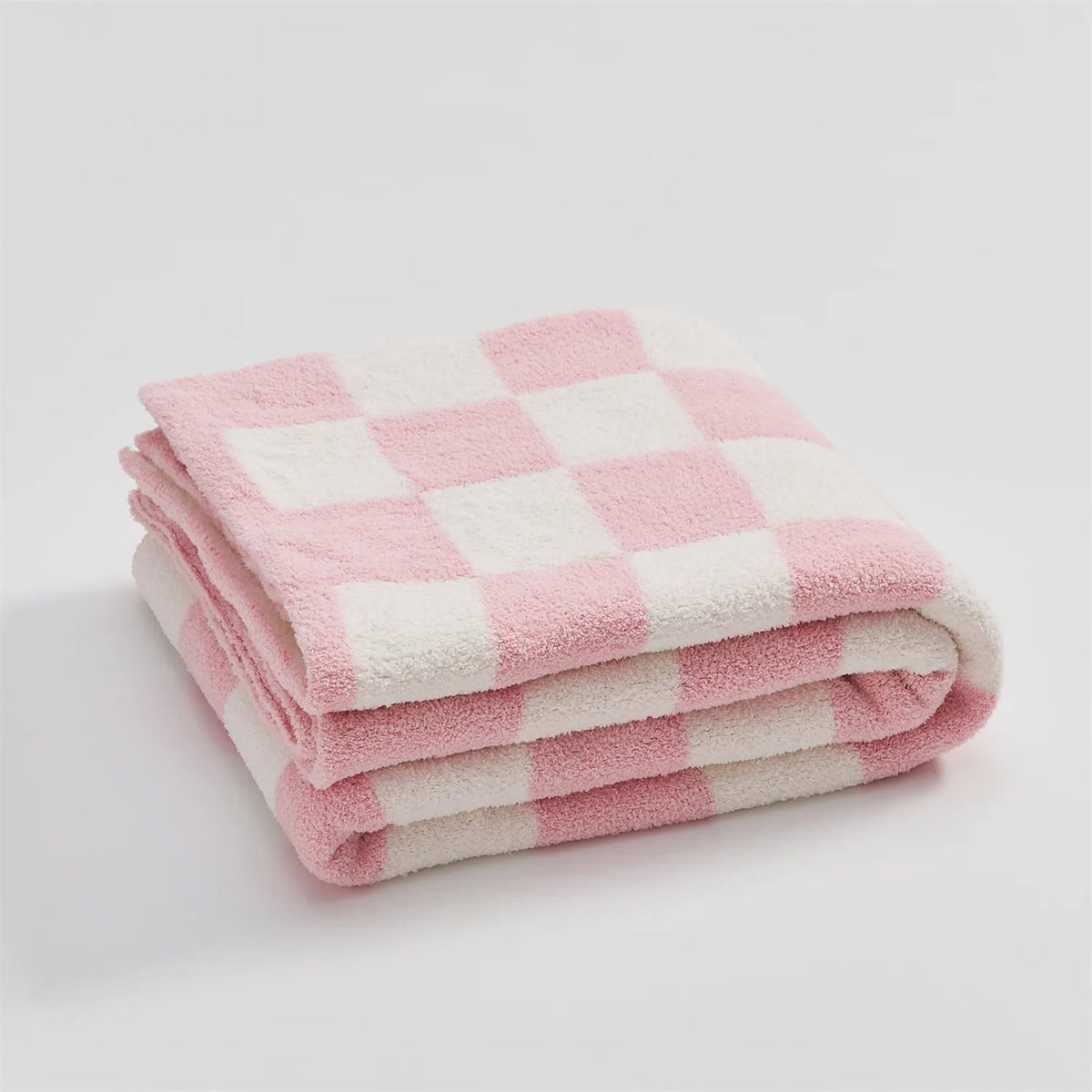Knitted teddy throw with a checkerboard pattern over an armchair - pink