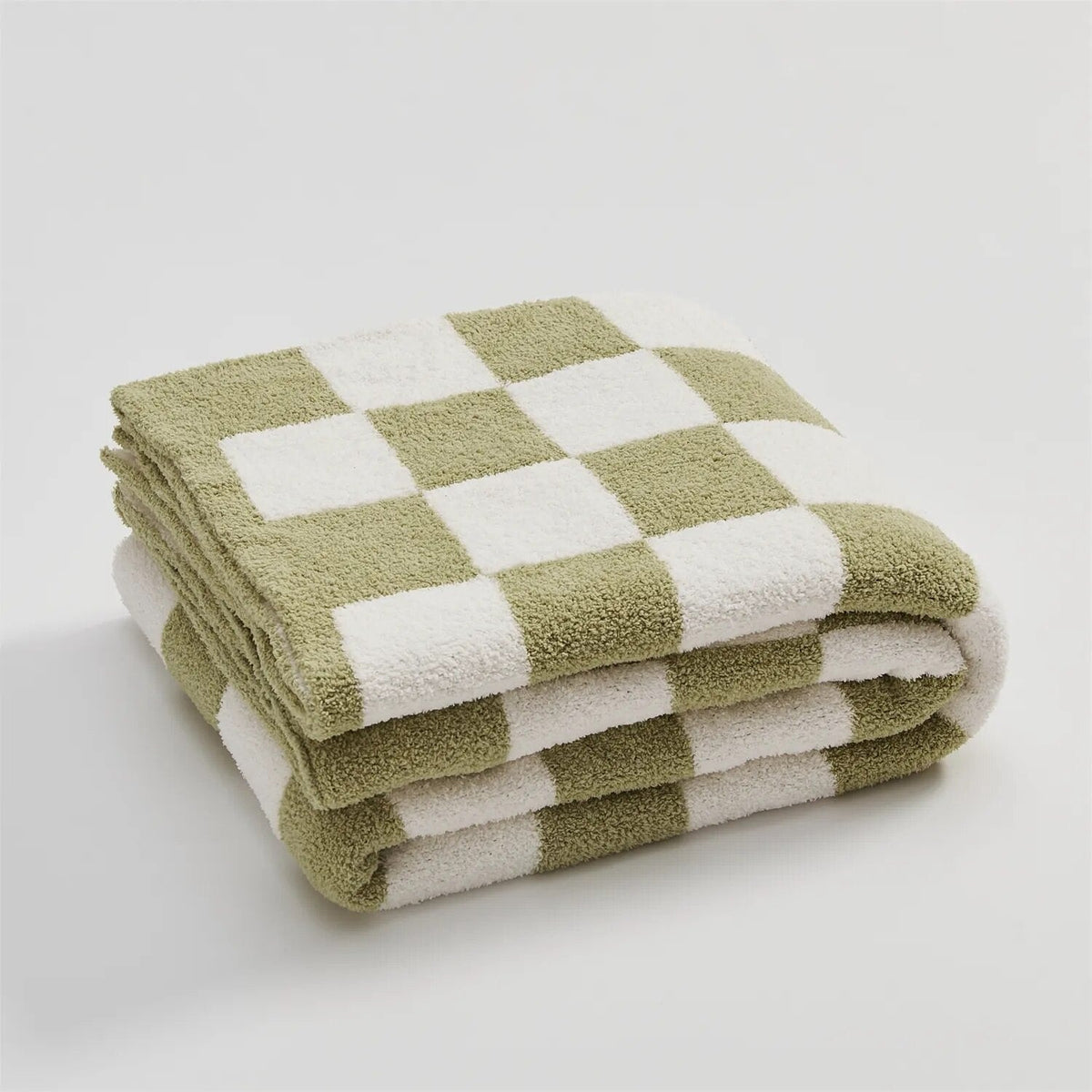 Knitted teddy throw with a checkerboard pattern over an armchair - sage green
