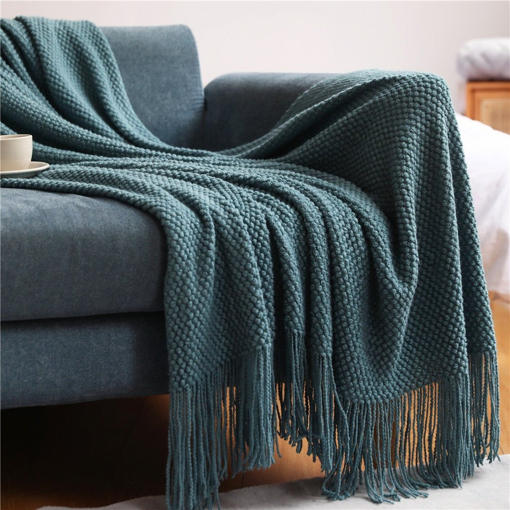 Knitted throw with a bobble texture and tassels over a sofa - petrol blue