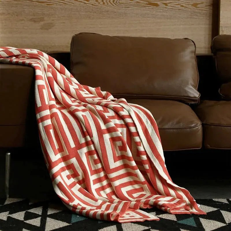 Knitted throw with a geometric pattern over a brown sofa - rust