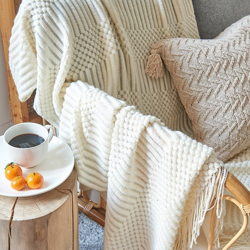Knitted throw with a Scandinavian pattern and tassels over a chair - cream
