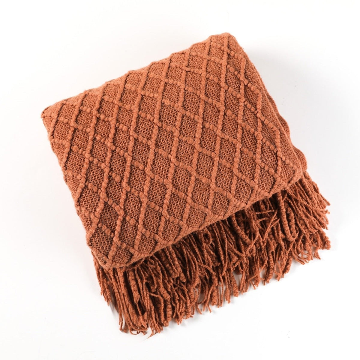 Knitted throw with a Scandinavian pattern and tassels over a chair - terracotta