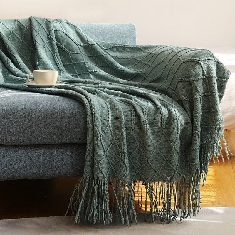 Knitted throw with a Scandinavian pattern and tassels over a chair - dark green