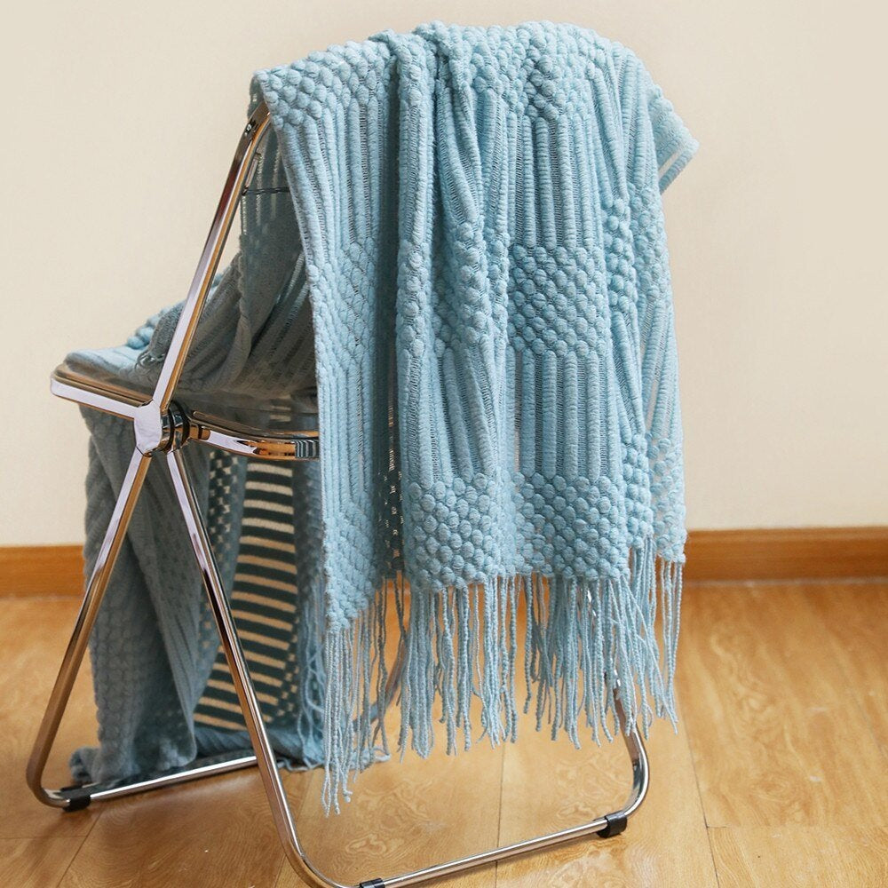 Knitted throw with a Scandinavian pattern and tassels over a chair - light blue