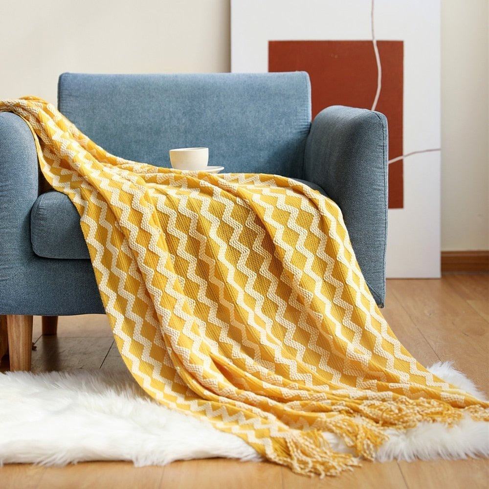 Knitted throw with a Scandinavian pattern and tassels over a chair - yellow and white zigzag