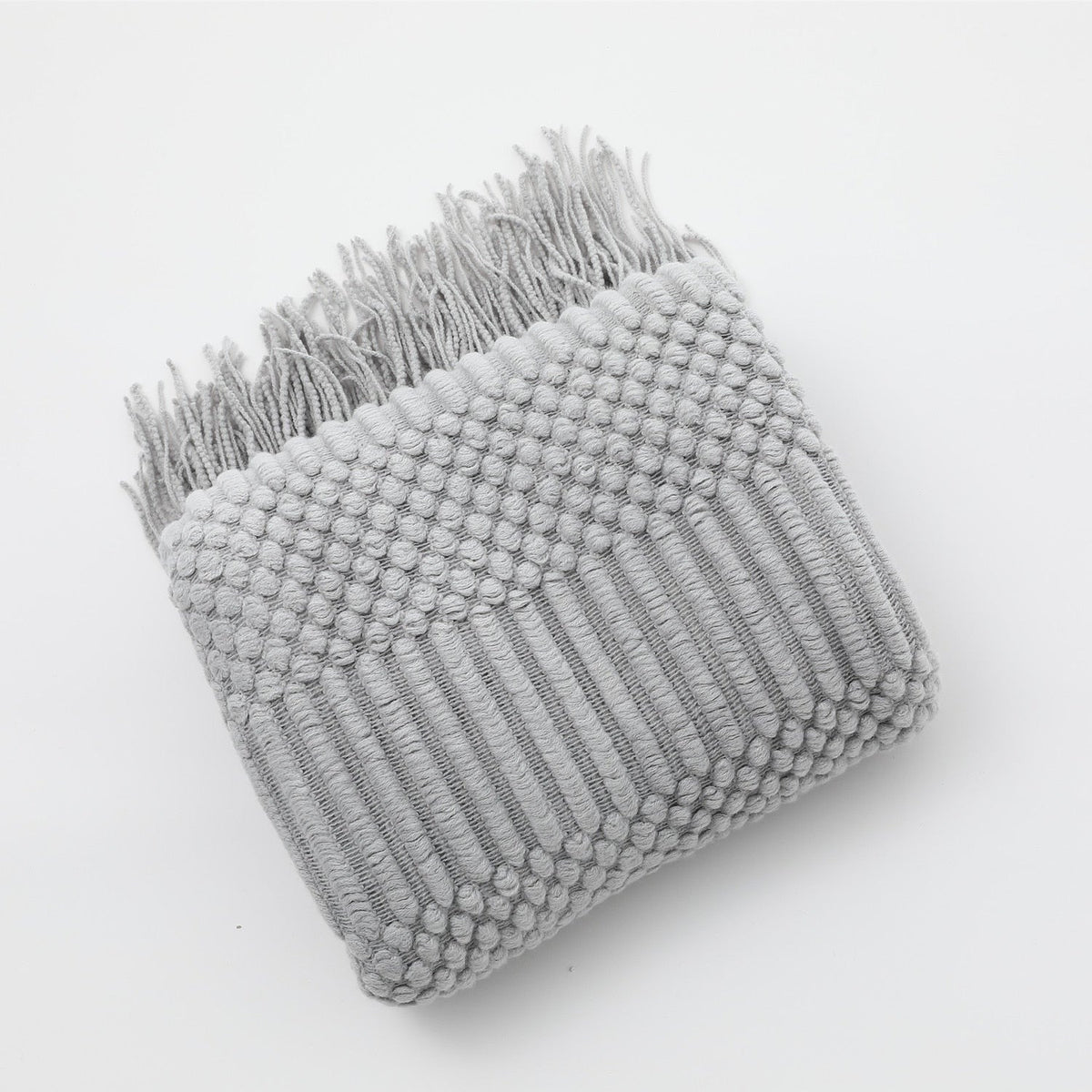 Knitted throw with a Scandinavian pattern and tassels over a chair - light grey