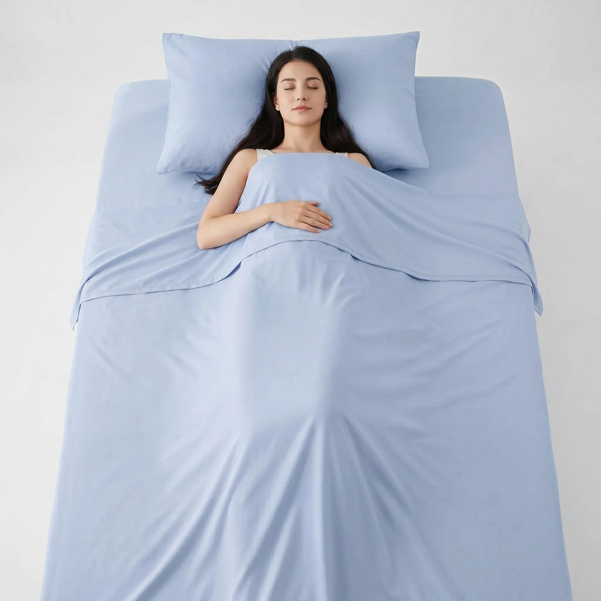 Thin smooth summer blanket over a sleeping woman in bed - light blue