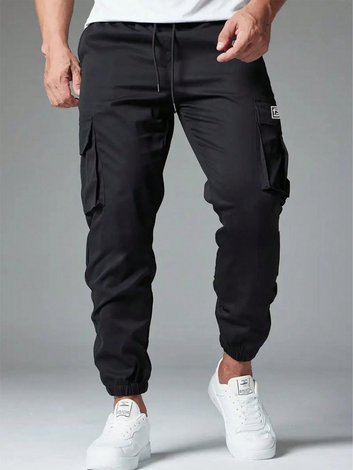 Cargo trousers for men with a drawcord waist, thigh flap pockets and elastic cuffs at the ankle - black