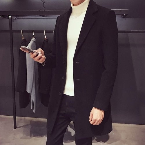 Men's black longline coat worn over a white roll neck