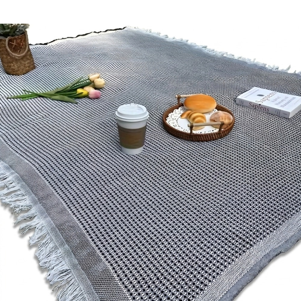 Picnic blanket of 180 x 180 cm with a waffle weave and fringe on the grass - black and white