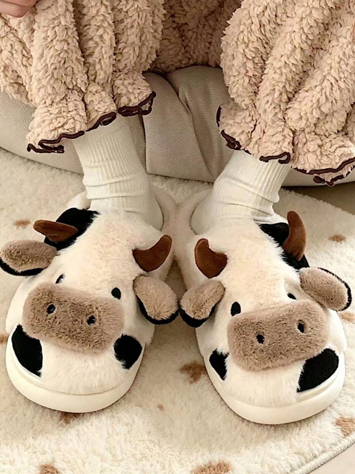 Plush cow slippers with little horns, ears and a snout on the toe and spots on the sides - black/white