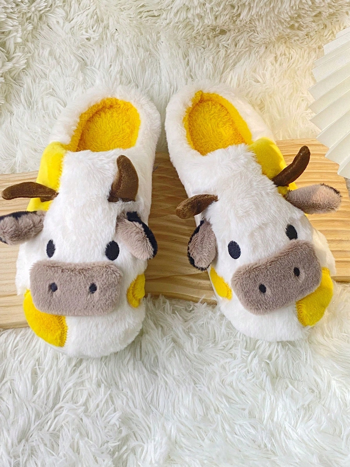 Plush cow slippers with little horns, ears and a snout on the toe and spots on the sides - yellow/white