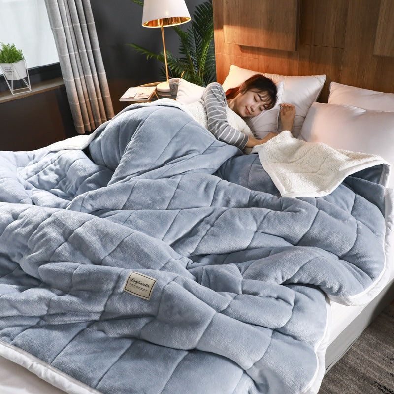 Quilted flannel fleece blanket with a sherpa reverse on a bed - blue grey