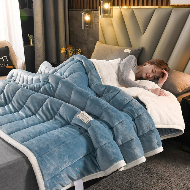 Quilted flannel fleece blanket with a sherpa reverse on a bed - steel blue