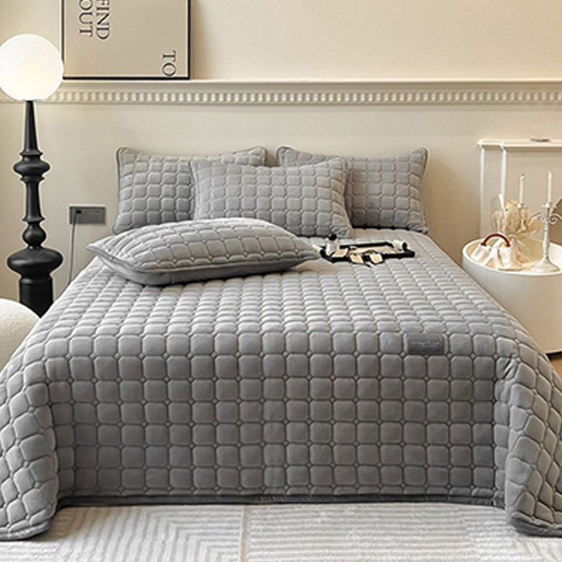Quilted teddy bedspread with a square pattern on a double bed - grey