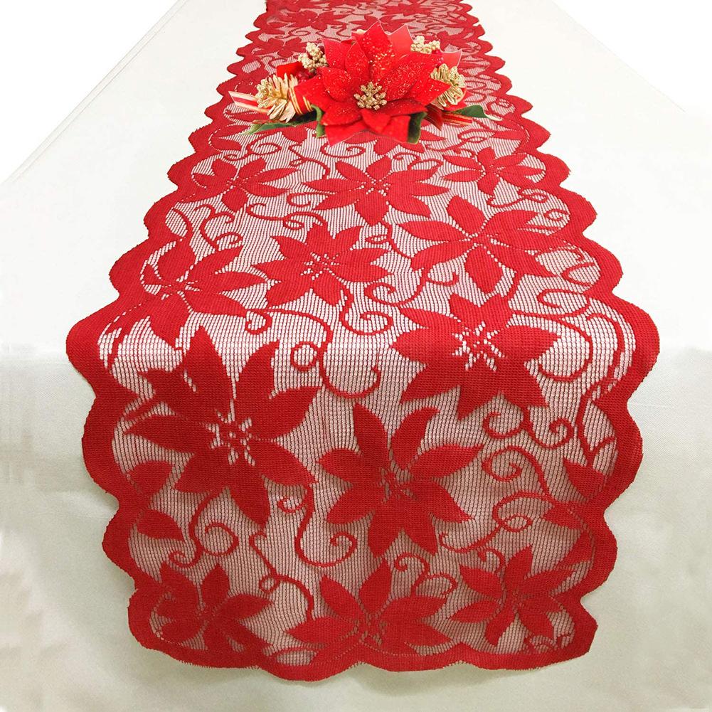 Red lace Christmas table runner with poinsettias and a scalloped edge on a table