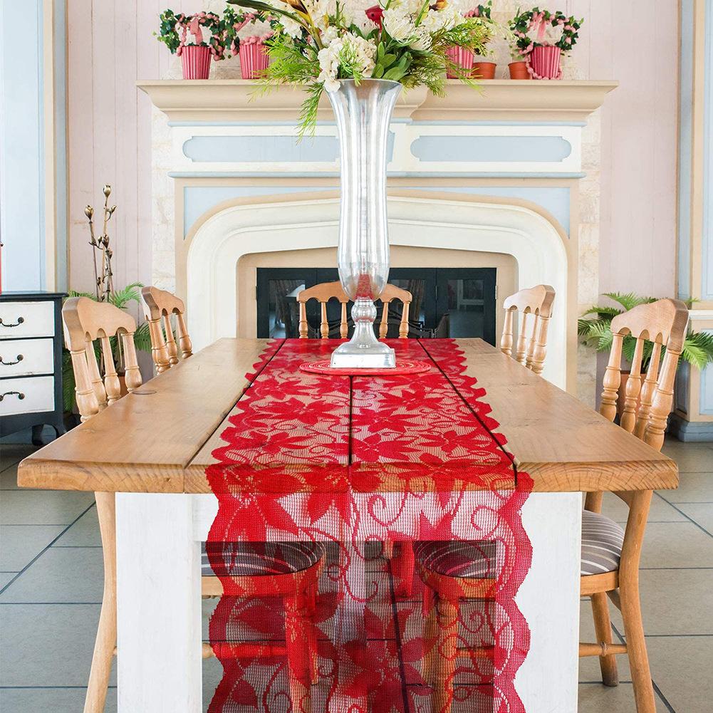 Red lace Christmas table runner with poinsettias and a scalloped edge on a table