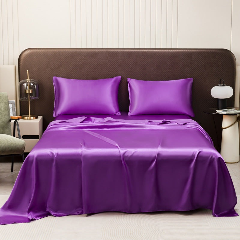 Satin sheet set with fitted sheet, flat sheet and two pillowcases on a bed - purple