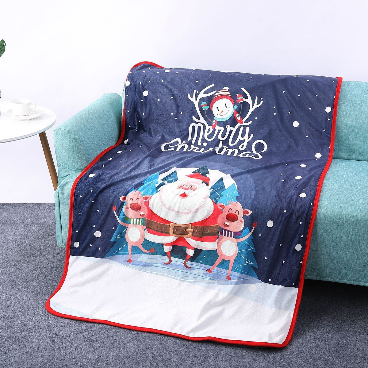 Soft Christmas blanket with a festive print, draped over a sofa - navy father christmas and reindeer