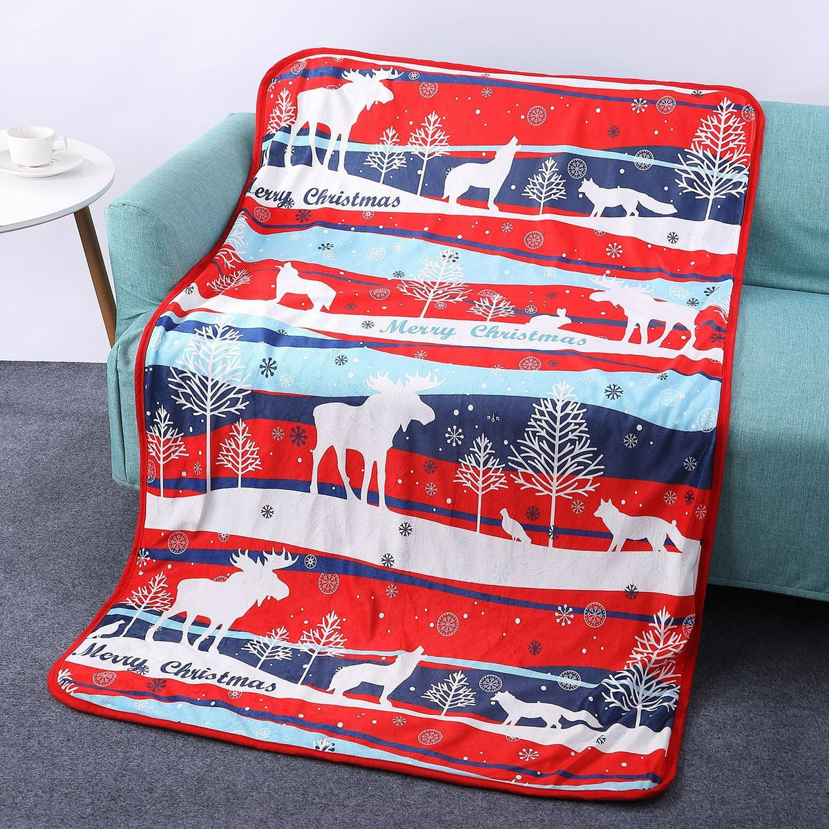 Soft Christmas blanket with a festive print, draped over a sofa - all-over moose stripes