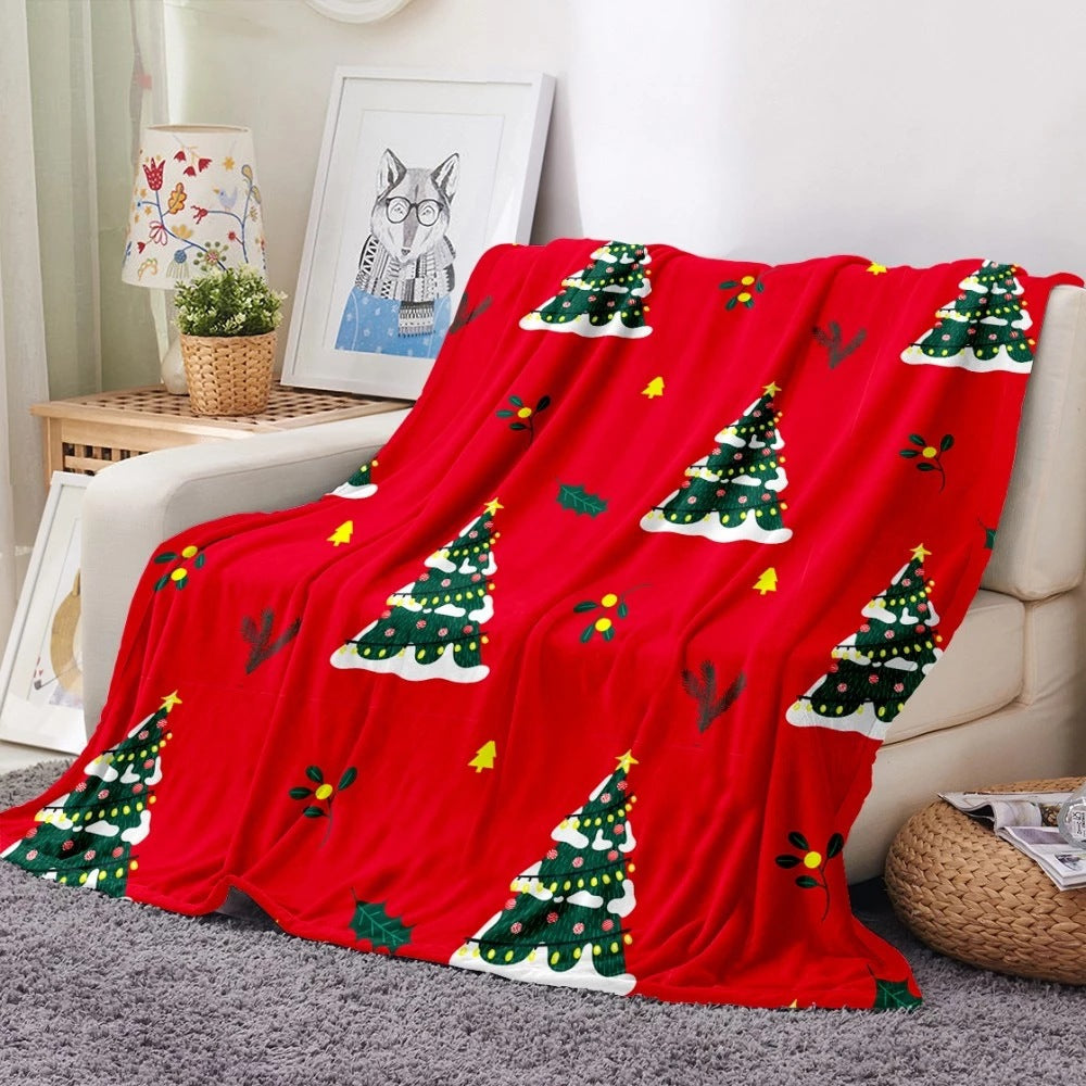 Soft fleece Christmas blanket with an all-over festive print on a sofa - red christmas trees