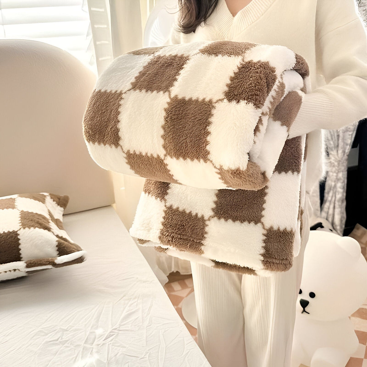 Teddy fleece blanket with a checkerboard pattern, folded in someone's arms - brown